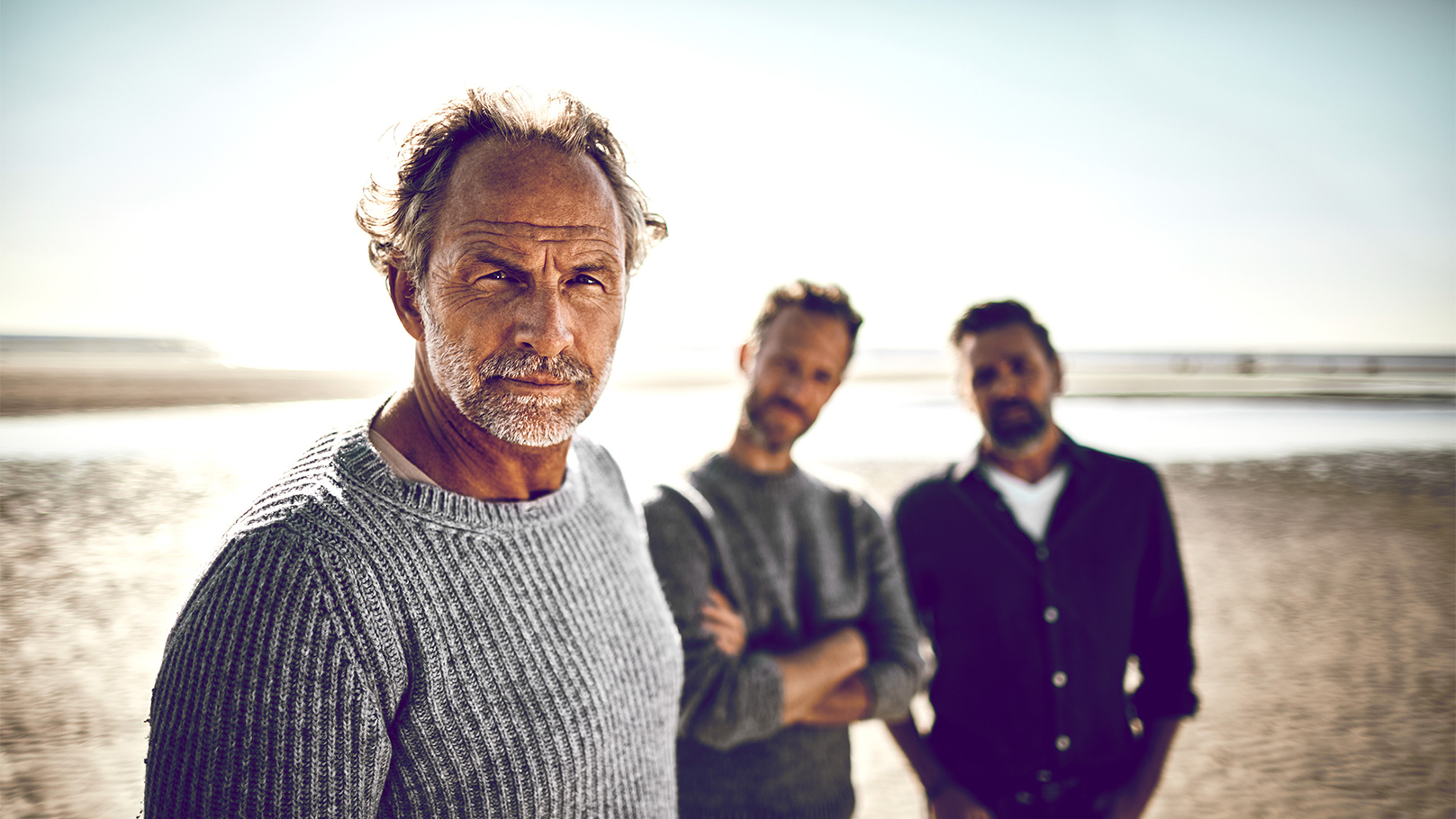 Father and sons stood on a beach